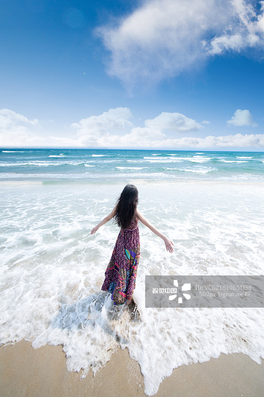 年轻女人站在海边张开双臂