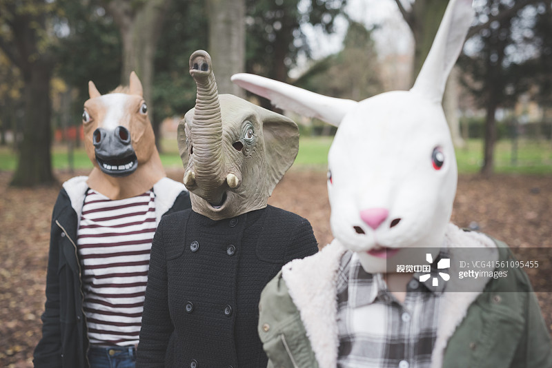 Three sisters wearing animal masks posing in park圖片素材