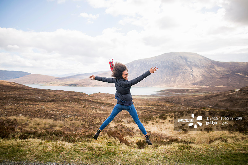 Mid adult woman in mountains doing star jump, Isle of Skye, Hebrides, Scotland圖片素材