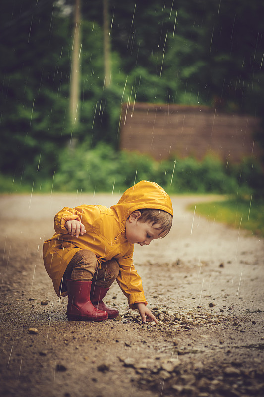 小男孩在雨中在馬路上玩耍圖片素材