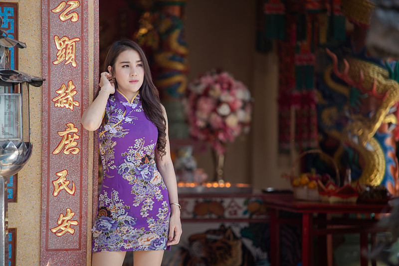 中國婦女穿著傳統旗袍站在中國寺廟。圖片素材