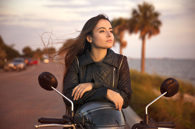 年輕女子在街上騎摩托車的特寫圖片下載