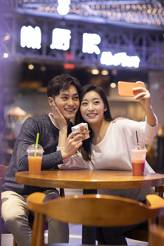快樂的年輕情侶在商場自拍圖片下載