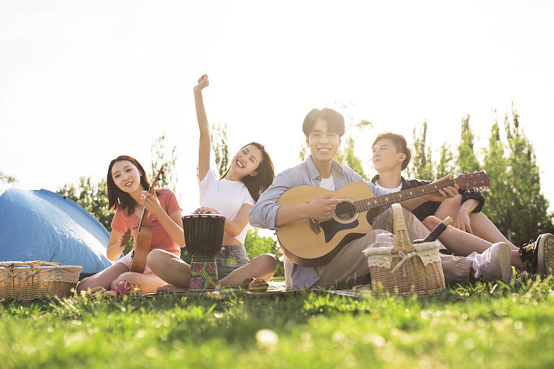 快樂的年輕人在戶外野餐演奏音樂圖片素材