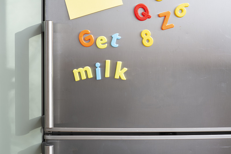 銀色冰箱上的彩色磁性字母上寫著“牛奶與空白便利貼”圖片素材
