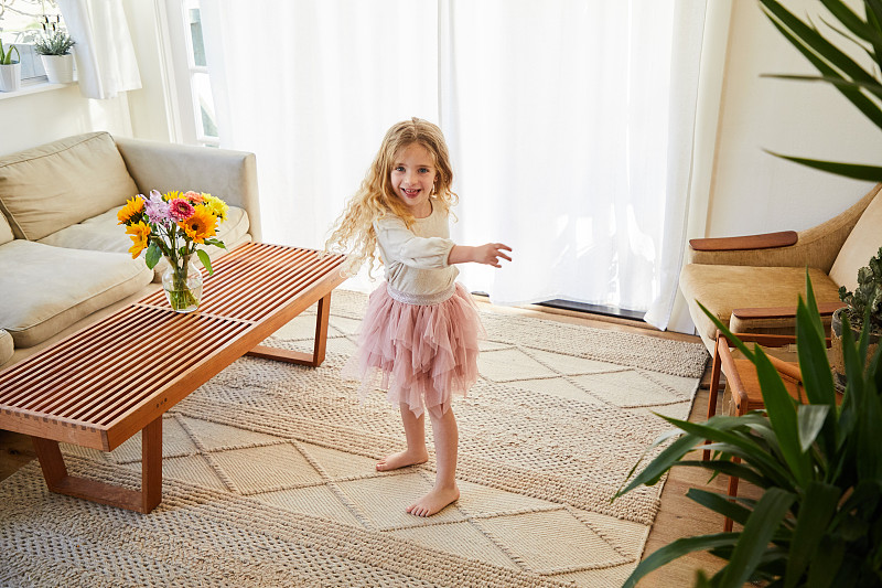 微笑的小女孩穿著芭蕾舞裙在家里跳舞圖片素材