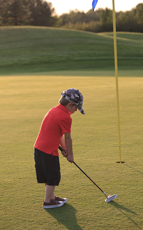 年輕的少年高爾夫球手在高爾夫球場上打球圖片素材