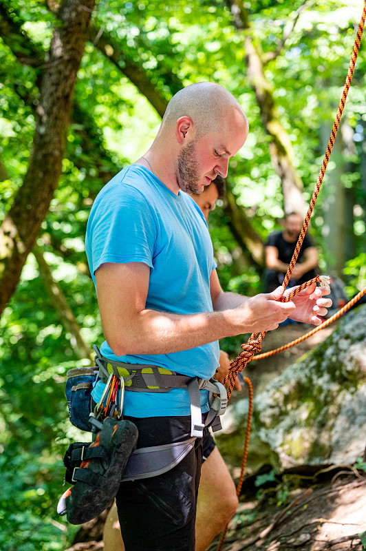 男運動員在戶外攀巖時系繩結圖片素材