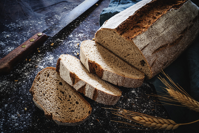 全谷物黑麥面包條，用老式的小刀蓋在深色的木頭上圖片素材