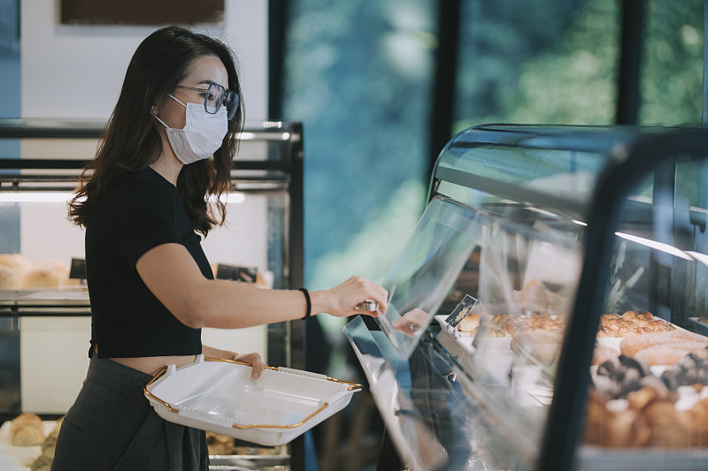 亞洲中國美麗的女人買糕點從一個咖啡館選擇拿著一個托盤圖片素材