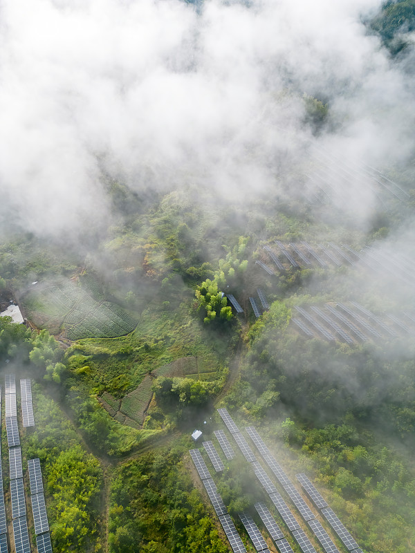 從無人機的視角看，山坡上的太陽能電池板在云霧中攝影圖片