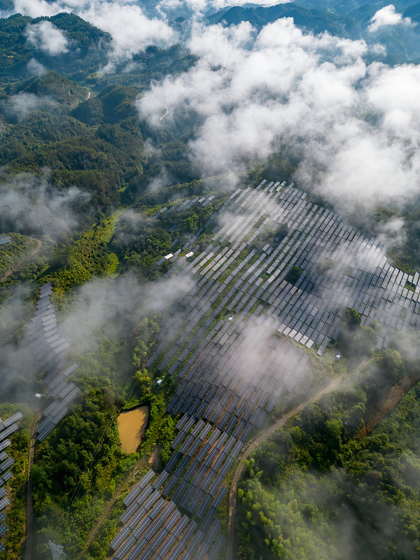 從無人機的視角看，山坡上的太陽能電池板在云霧中攝影圖片