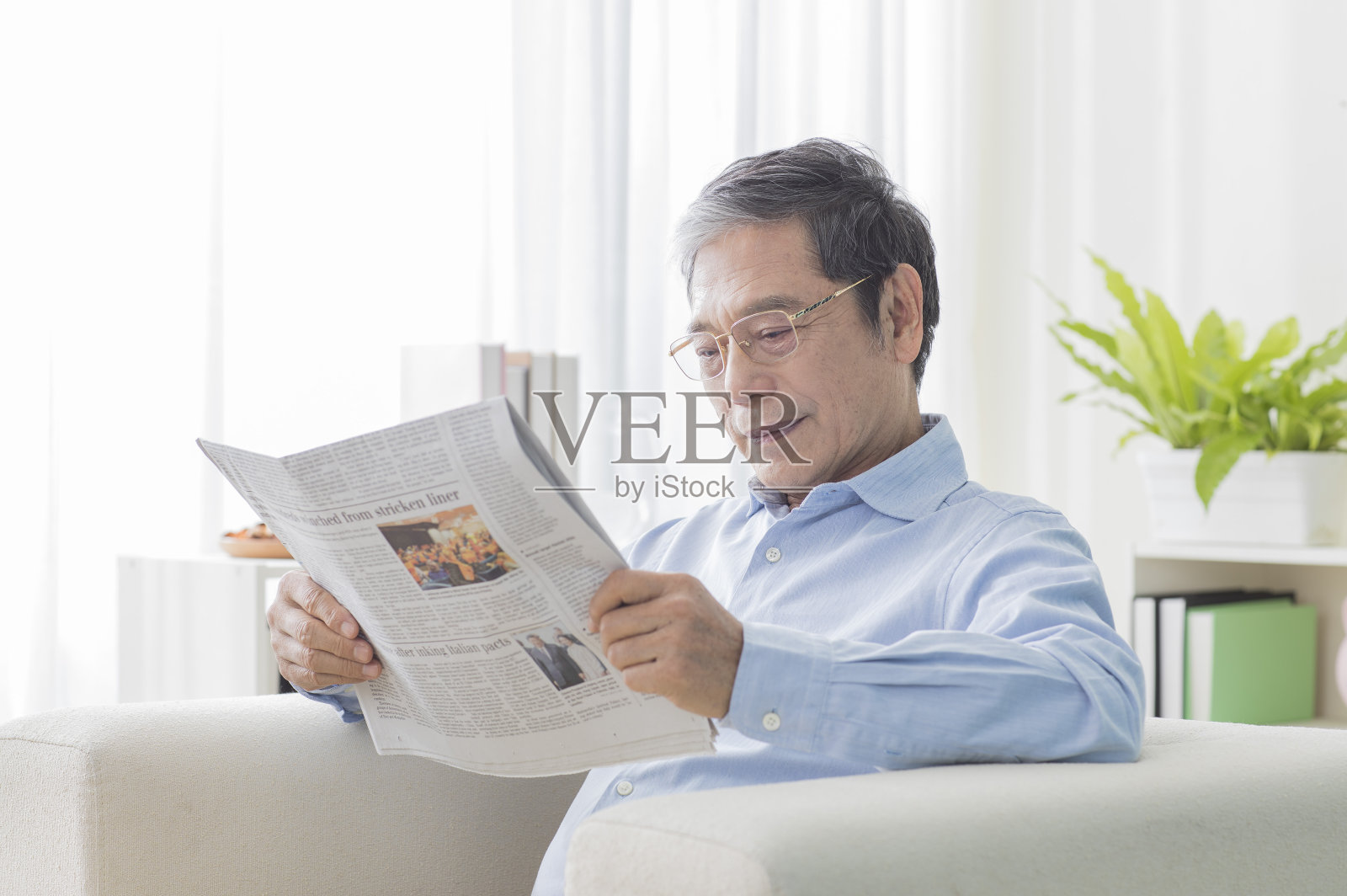 老年男人坐在沙发上看报纸照片摄影图片