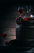 在黑暗的酒窖里装红酒的酒桶、醒酒器和酒杯图片素材