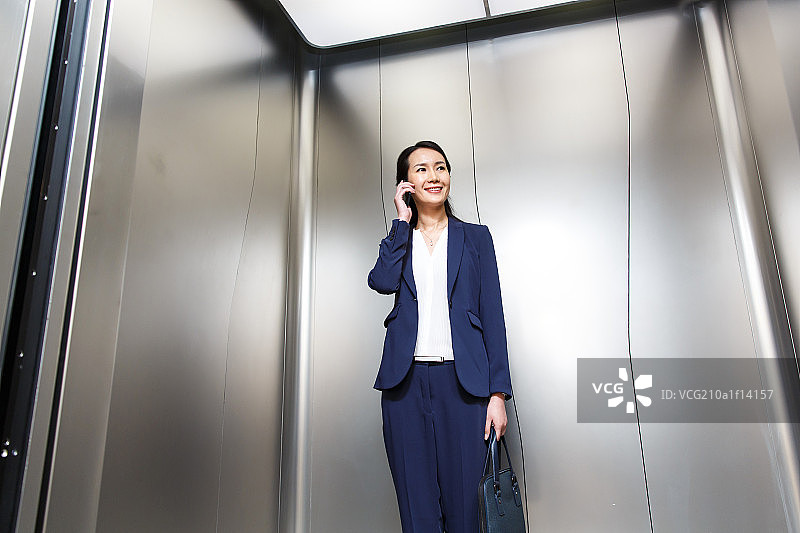 成功的商务女性在电梯里打电话图片素材