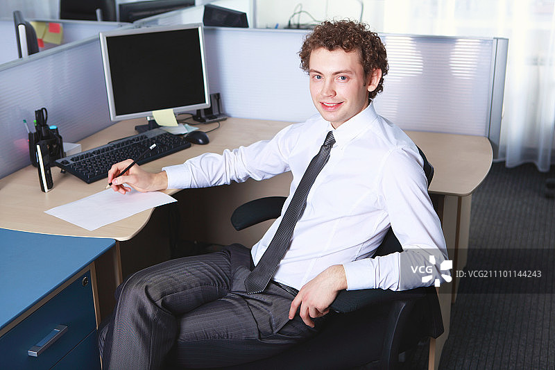 一个年轻的商人穿着正装在办公室里微笑着图片素材