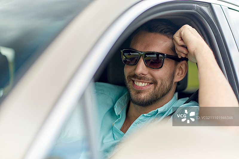 公路旅行，交通，旅行和人的概念-快乐微笑的男人在太阳镜驾驶汽车图片素材