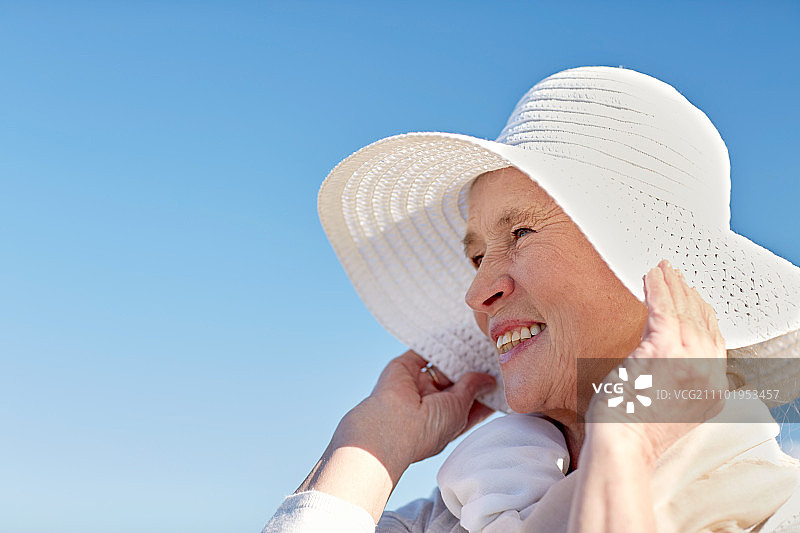 年龄，休闲和人的概念-快乐老年妇女在夏天的海滩上戴太阳帽图片素材