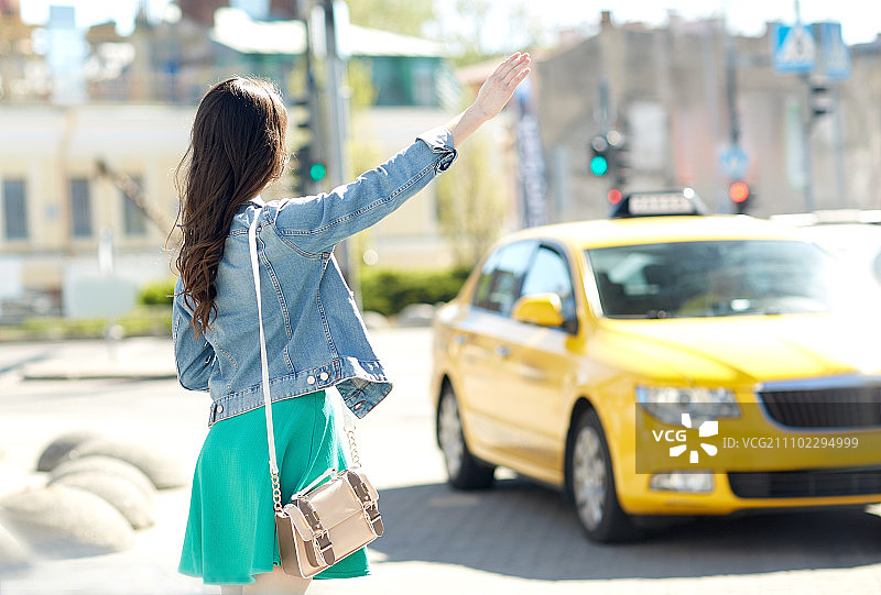 手势，交通工具，旅游，旅游和人的概念-年轻女性或少女在城市街道上搭乘出租车或搭便车图片素材