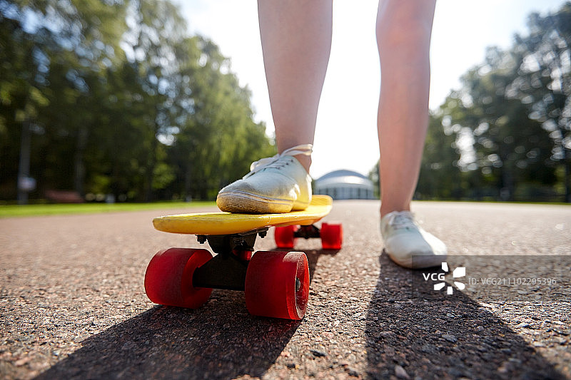 滑板，休闲，极限运动和人的概念-近距离十几岁的女孩的腿骑短现代巡洋舰滑板在道路上图片素材