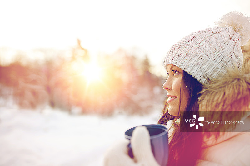 人、季节、饮品与休闲理念——快乐的年轻女子在冬季户外拿着茶杯图片素材