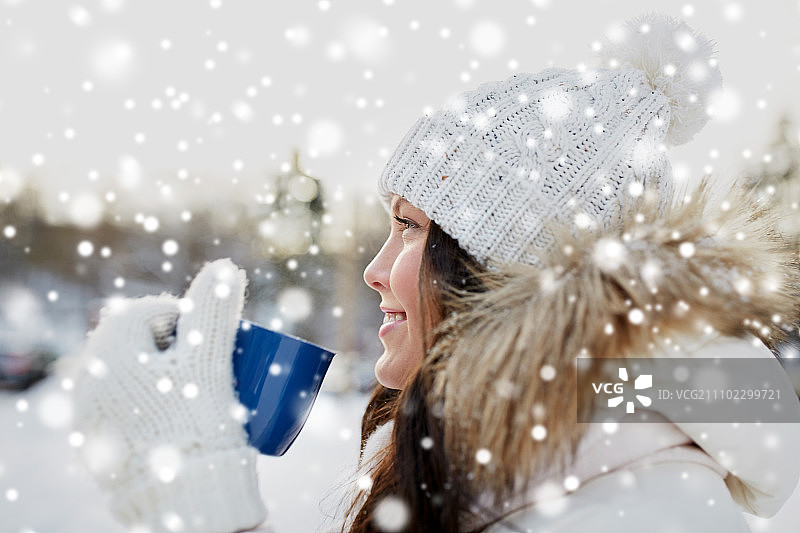 人、季节、饮品与休闲理念——快乐的年轻女子在冬季户外拿着茶杯图片素材