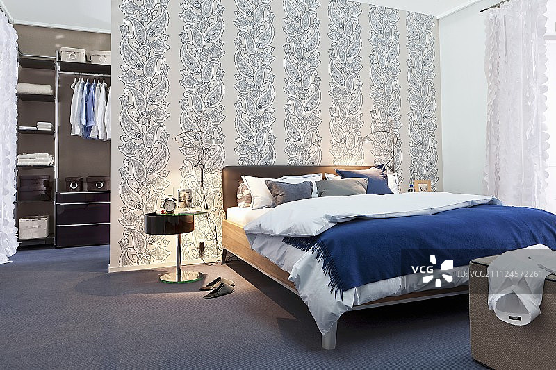 卧室有床，床头灯，衣柜和图案墙纸图片素材