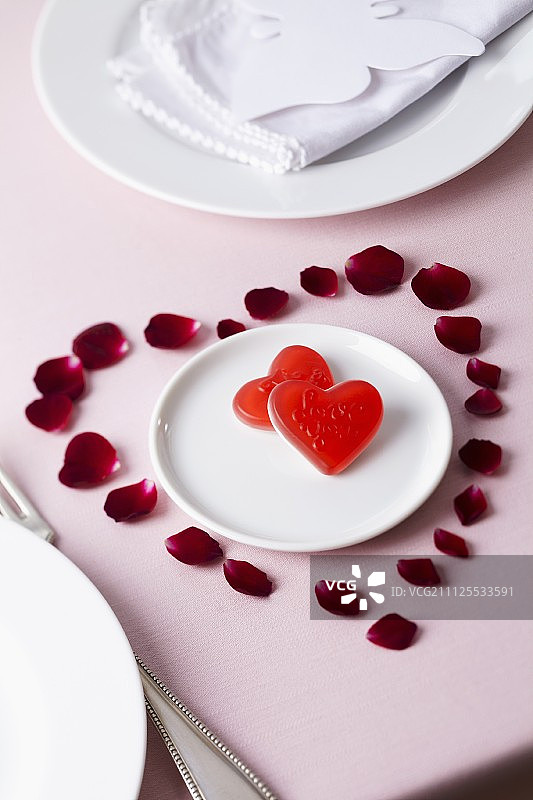 盘子里的糖果周围是心形的玫瑰花瓣图片素材