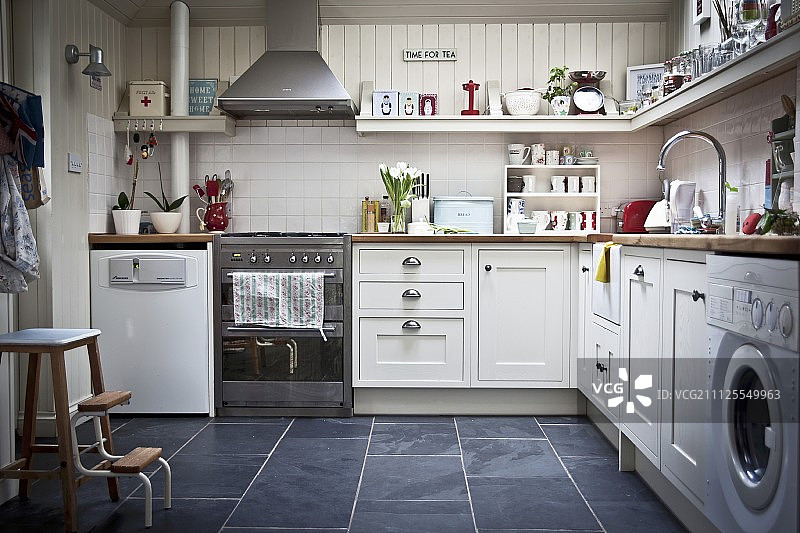 厨房配备白色家具，配备的电器和器皿在壁挂式架子上图片素材