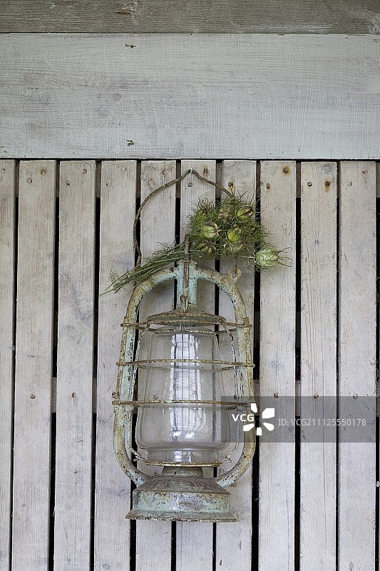 木板条墙上挂着一盏枯了的花园花的旧灯笼图片素材
