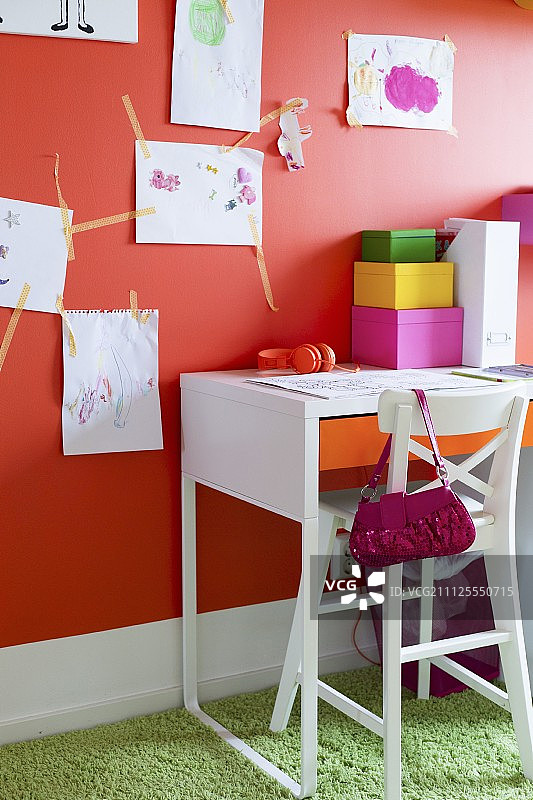 高高的，白色的椅子在桌子下面的孩子的画在橙色的墙上图片素材