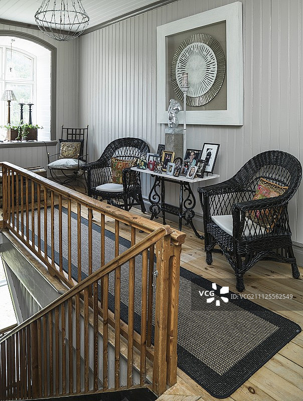 黑色的柳条椅和有旧木栏杆的控制台桌上的相框图片素材