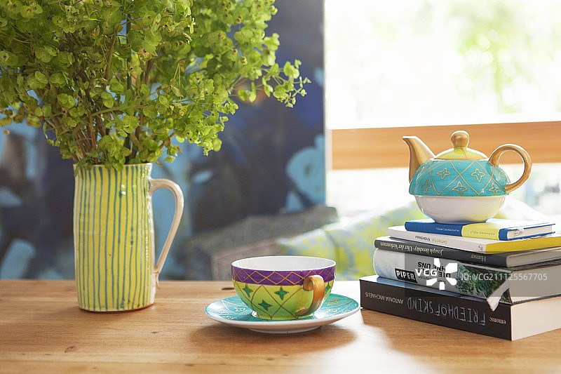 茶杯旁边的茶壶在一堆书和女士的斗篷陶瓷壶图片素材