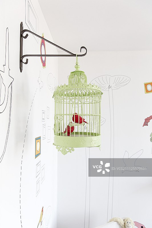 金属鸟饰品在绿色古董鸟笼挂在金属墙支架图片素材