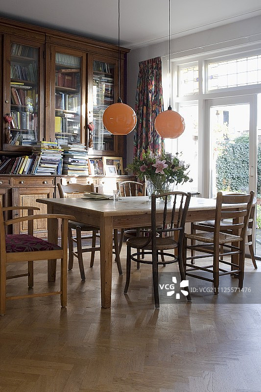 客厅角落的球形吊灯下设有木桌和各种木椅的用餐区图片素材