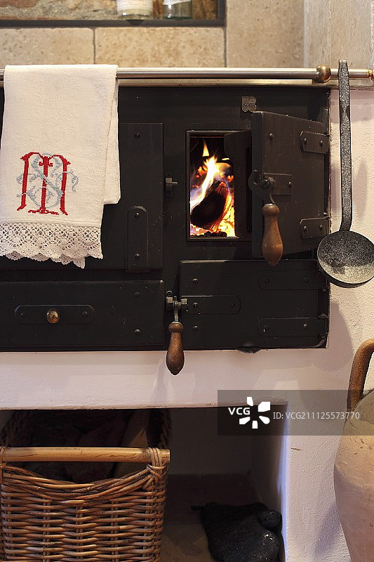 木柴烧制的炊具，布和包挂在毛巾轨上，透过打开的火箱门可以看到火图片素材