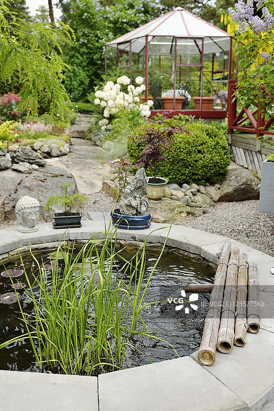 日本式，石边池塘与竹水喷口和佛像前六角形温室图片素材
