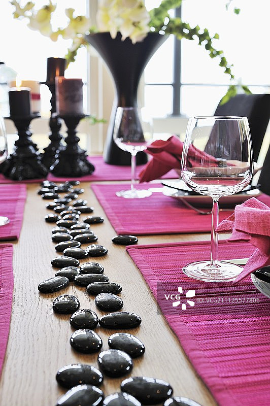 餐桌上摆放着喜庆的粉色餐垫和闪亮的黑色鹅卵石图片素材