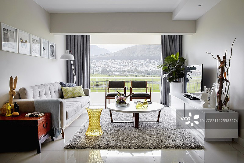 客厅沙发和低矮餐具柜，透过玻璃墙可以看到景观图片素材