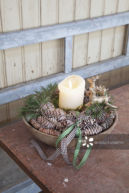柱状蜡烛、雄鹿装饰品和松果排成碗状图片素材