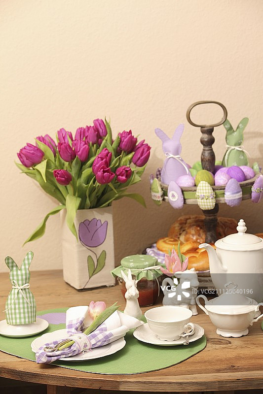 复活节餐具，花瓶的郁金香，糕点和复活节装饰品的蛋糕架在木桌上图片素材