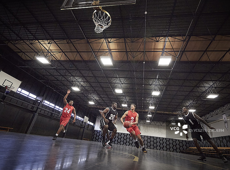 年轻的男子篮球运动员在体育馆的球场上打篮球图片素材