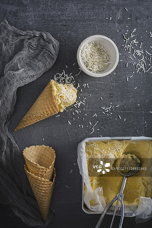 自制芒果冰淇淋与磨碎的巧克力和冰淇淋蛋筒和一个容器图片素材