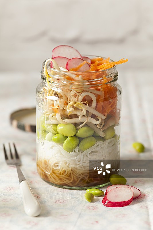 日本东方毛豆生午餐罐用叉子和盖在布表面图片素材
