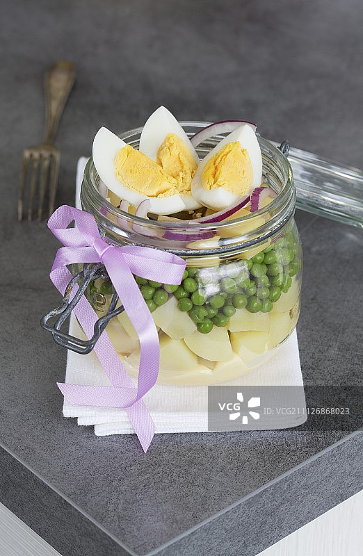一份蔬菜沙拉，里面有土豆、豌豆、奶酪、洋葱、蛋黄酱和鸡蛋，放在一个玻璃罐子里图片素材