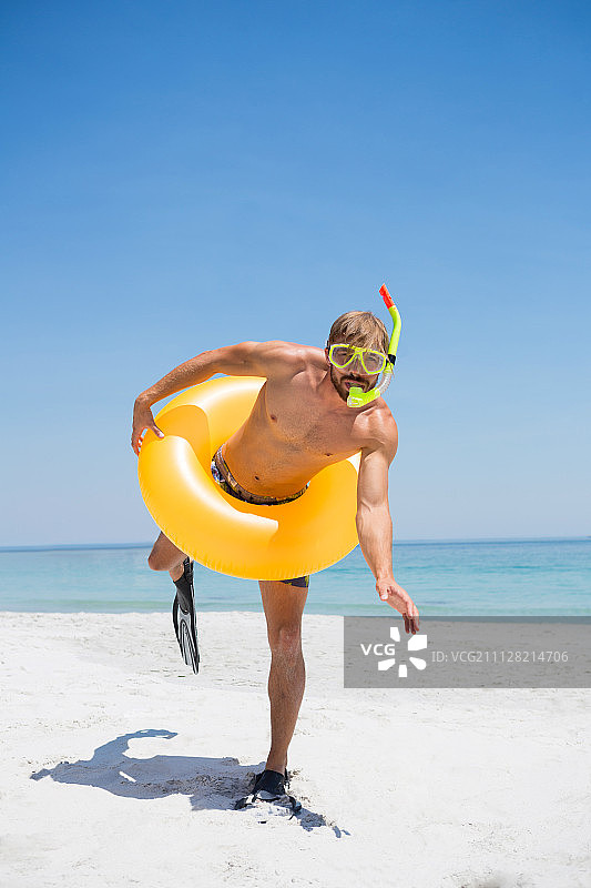 好玩的男人戴着通气管，在阳光明媚的日子里站在海滩上图片素材