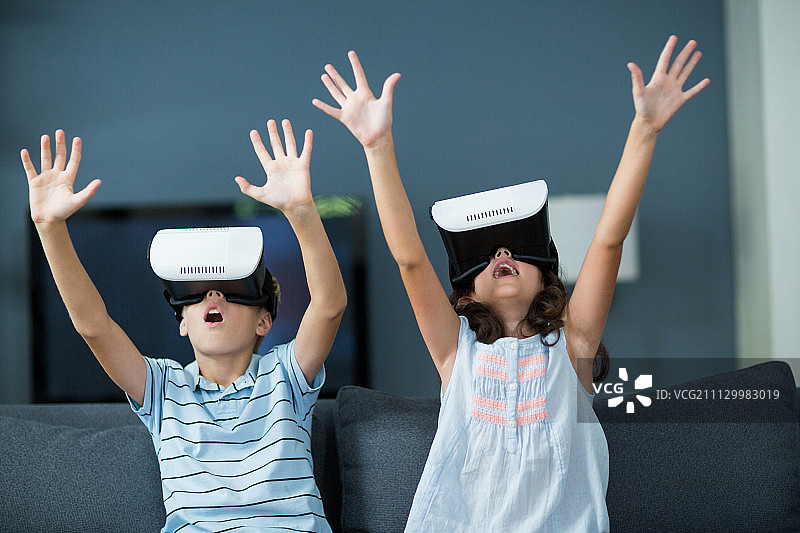 兄弟姐妹在家里客厅使用虚拟现实头盔图片素材
