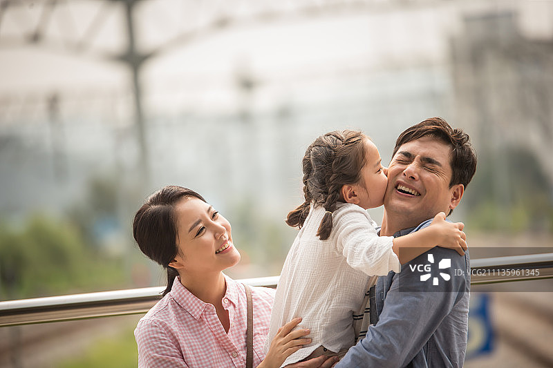 幸福家庭站在站台，女儿亲吻父亲的脸颊图片素材