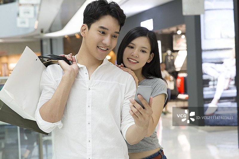 年轻情侣在商场用手机图片素材