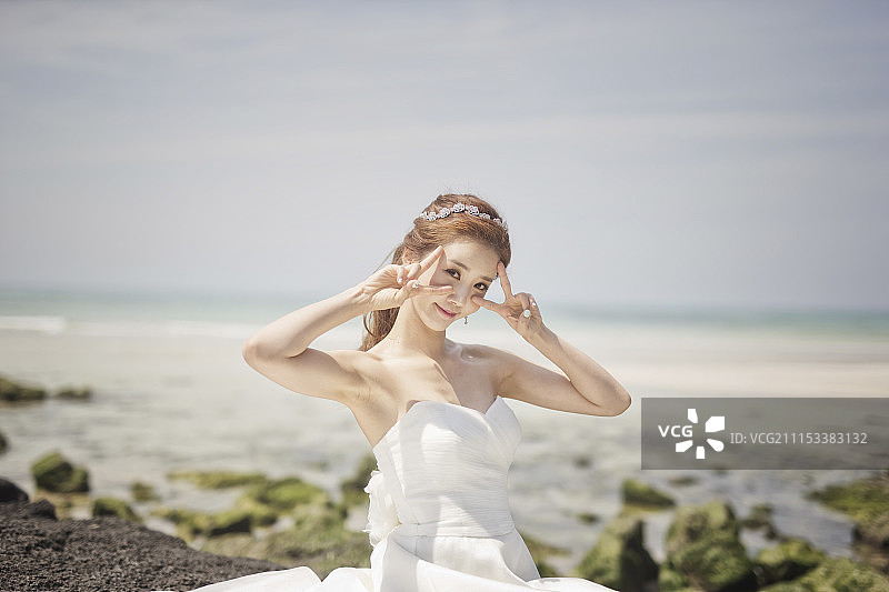 穿着婚纱的女人在海滩摆姿势图片素材